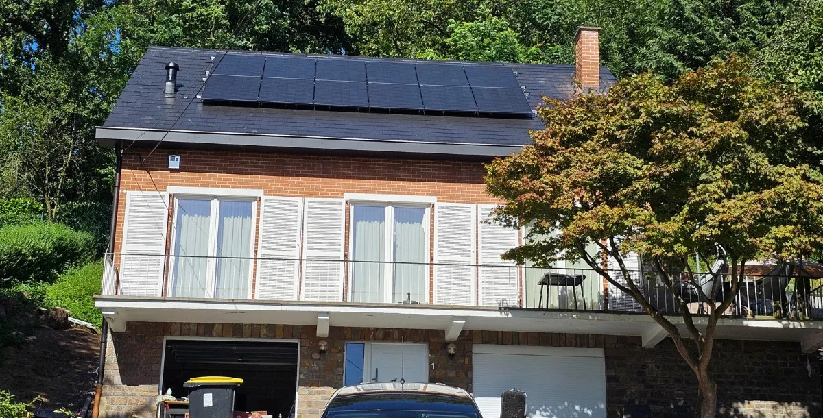 Photo de la maison à Mons avec une toiture récemment rénovée et isolée, équipée de panneaux solaires photovoltaïques. Les panneaux sont montés sur des rails pour maximiser la ventilation et améliorer l'efficacité énergétique de l'installation.