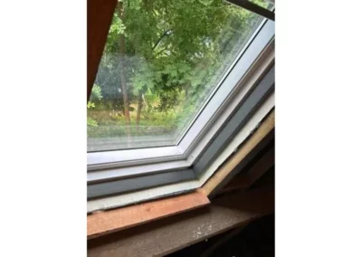 Fenêtre de toit Velux sur un isolant de toiture à Mons. Le cadre de la fenêtre est ajusté pour garantir une étanchéité parfaite et une isolation thermique optimale, permettant à la lumière naturelle d'entrer tout en maintenant le confort intérieur.