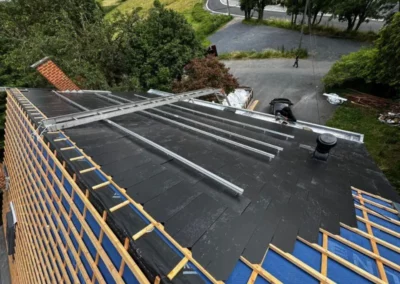 Fixation des rails de support pour panneaux photovoltaïques sur la toiture en ardoise par TS Rénovation à Mons, assurant une installation sécurisée et durable des panneaux solaires.