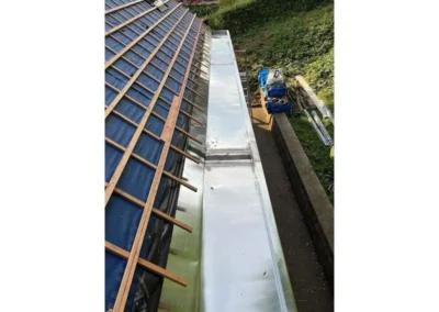 Installation du bac de corniche en métal sur une toiture qui a été rénovée. Le bac de corniche est conçu pour assurer une évacuation optimale de l'eau de pluie et protéger la structure de la maison.