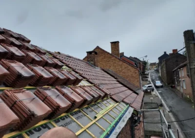 Pose des tuiles Koramic sur une toiture en cours de rénovation à Roux. Les tuiles sont alignées pour assurer une couverture solide et durable, protégeant la maison des intempéries.