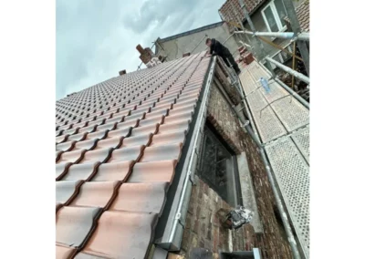 Iinstallation de la gouttière au pied de la toiture. La gouttière est fixée pour garantir un drainage efficace de l'eau de pluie et protéger la façade de la maison.