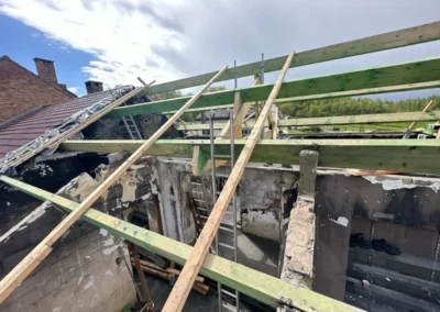 Rénovation de toiture. Pose des pannes en bois sur la ferme de charpente. Les pannes sont fixées pour créer une structure solide qui soutiendra la future couverture de toit.