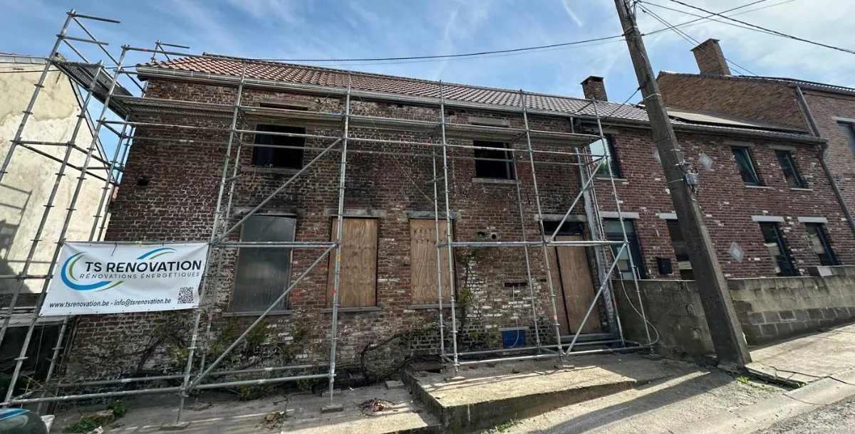 Maison en cours de rénovation à Roux, avec un échafaudage installé pour la pose d'une nouvelle toiture en tuiles. La rénovation inclut également la reconstruction du mur du pignon et l'installation d'une nouvelle charpente, réalisée par TS Rénovation, spécialiste en travaux de toiture dans la région de Charleroi.