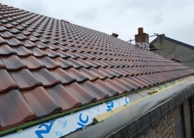 La toiture en tuiles achevée après des travaux de rénovation à Roux. Les tuiles sont uniformément posées, assurant une couverture robuste et durable pour protéger la maison des intempéries.