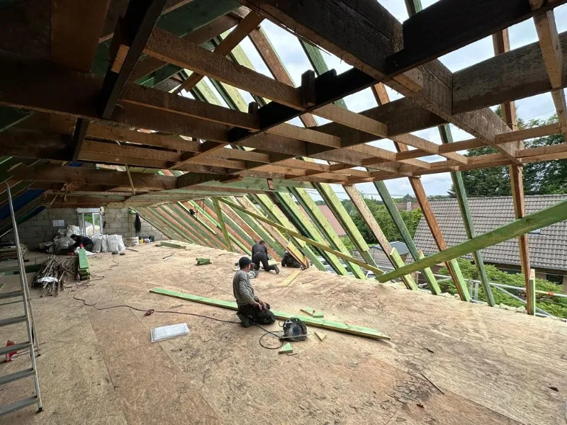 Rénovation sur la charpente de la toiture. Les ouvriers de TS Rénovation renforcent la structure en bois de la charpente, garantissant la stabilité de la toiture avant la pose de la couverture finale.