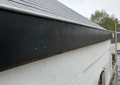 habillage de corniche noir sur une maison. Cette finition assure la protection contre les intempéries et donne un aspect moderne et propre à la toiture.