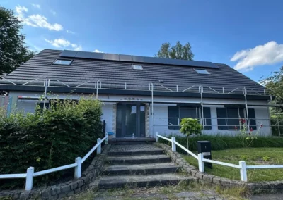 La maison située dans le brabant wallon en zone verte présente une toiture fraîchement installée avec des tuiles de couleur sombre et des panneaux solaires intégrés.