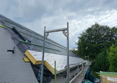 installation de l'isolation sur une toiture en pente pour un propriétaire à Rixensart. On distingue un écran de sous-toiture et des panneaux isolants en cours de pose, prêts à être recouverts par le matériau de couverture.